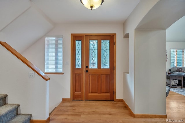 foyer entrance with light wood-style flooring, baseboards, and stairs
