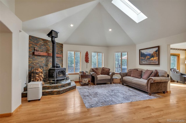living room with recessed lighting, wood finished floors, a wood stove, a skylight, and high vaulted ceiling