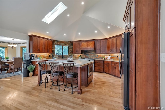 kitchen featuring stainless steel appliances, a center island, a kitchen breakfast bar, plenty of natural light, and custom exhaust hood