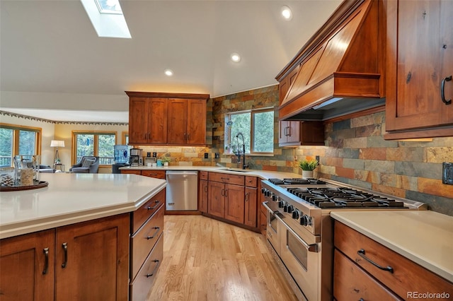kitchen with a sink, a skylight, brown cabinetry, stainless steel appliances, and premium range hood