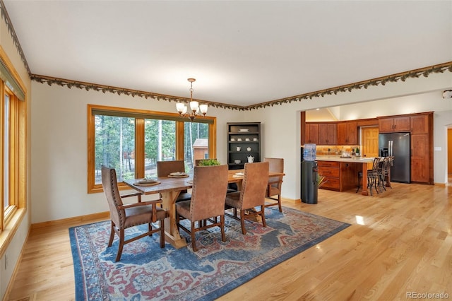 dining space with baseboards, a notable chandelier, and light wood-type flooring