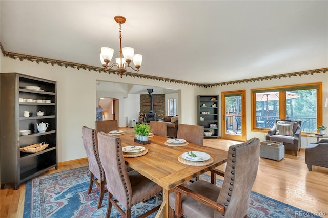 dining area with arched walkways, a healthy amount of sunlight, wood finished floors, and a chandelier