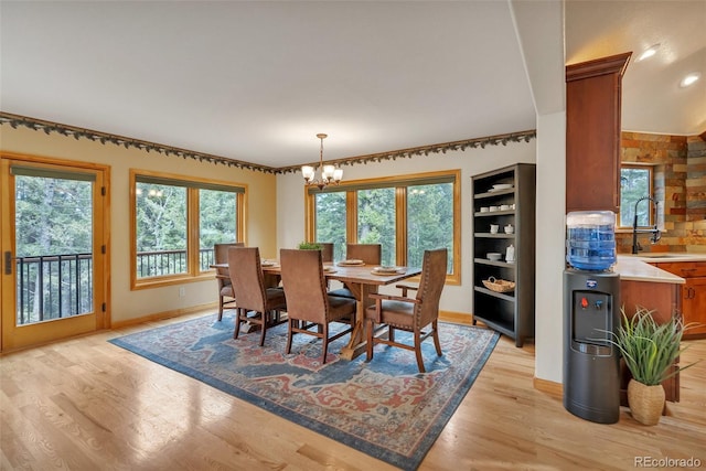 dining area featuring light wood-style flooring, baseboards, recessed lighting, and a notable chandelier