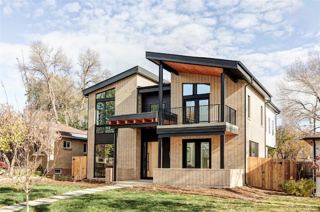 contemporary home featuring a balcony and a front lawn