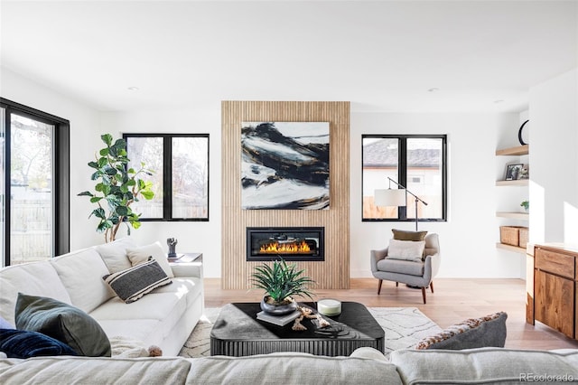 living room with a large fireplace and light hardwood / wood-style flooring