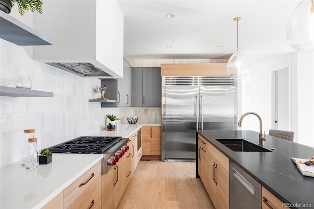 kitchen featuring backsplash, sink, light brown cabinetry, appliances with stainless steel finishes, and light hardwood / wood-style floors