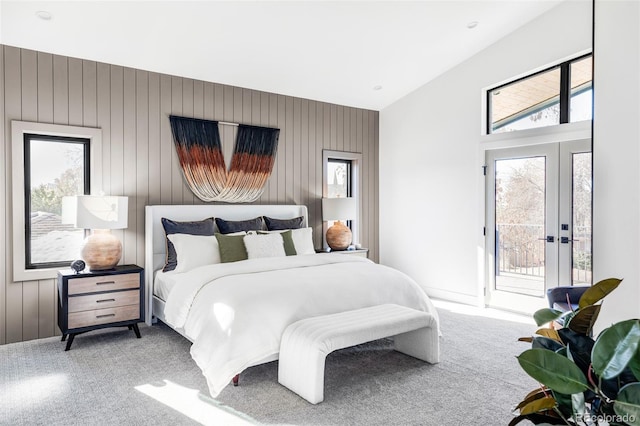 carpeted bedroom with access to outside and wooden walls