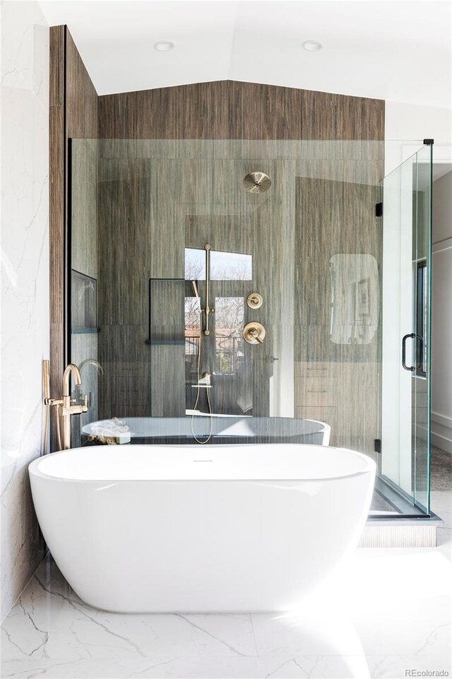 bathroom featuring separate shower and tub, tile walls, and lofted ceiling