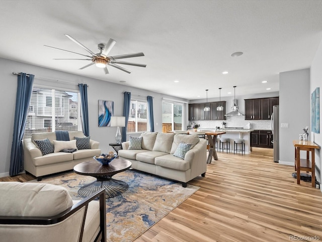 living room featuring light wood-style floors, a healthy amount of sunlight, a ceiling fan, and recessed lighting