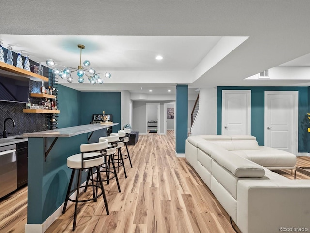 living area with light wood-style flooring, wet bar, recessed lighting, stairway, and baseboards