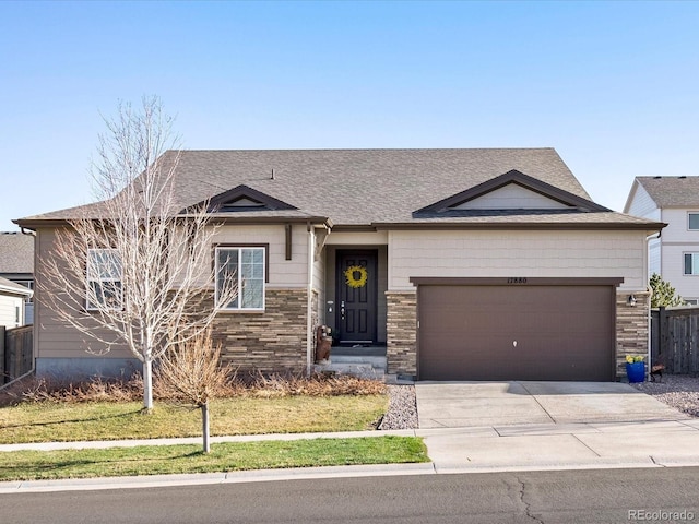 view of front of property featuring concrete driveway, stone siding, an attached garage, fence, and a shingled roof