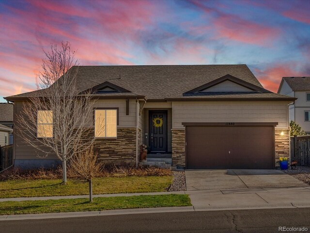view of front of home with driveway, stone siding, a garage, and roof with shingles