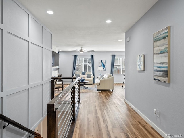 corridor featuring wood finished floors, baseboards, and recessed lighting
