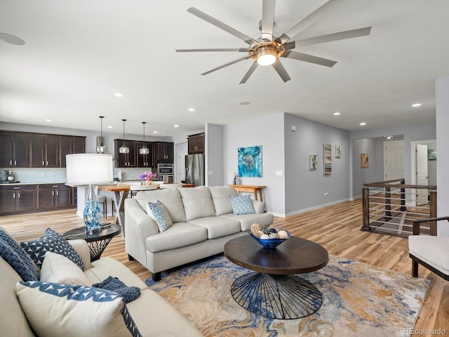 living area with recessed lighting, ceiling fan, light wood-type flooring, and baseboards