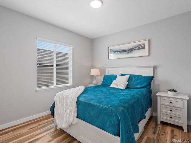 bedroom featuring multiple windows, baseboards, and wood finished floors