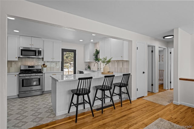 kitchen with white cabinetry, sink, kitchen peninsula, a breakfast bar, and appliances with stainless steel finishes