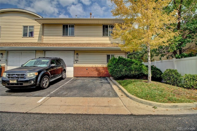 view of front of house featuring brick siding, fence, a garage, and driveway