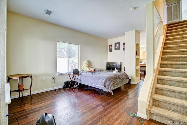 bedroom featuring arched walkways, visible vents, baseboards, and dark wood-style flooring