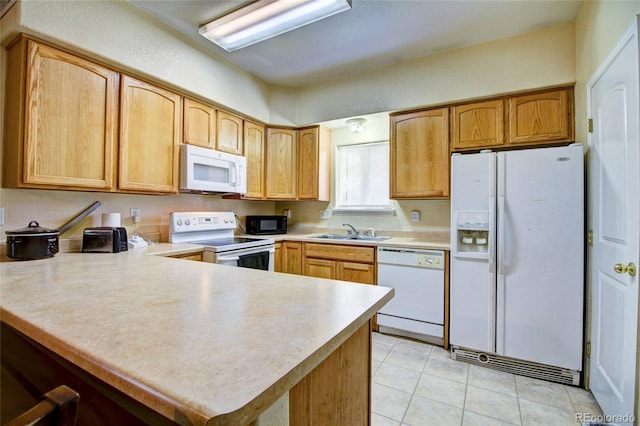 kitchen featuring light countertops, light tile patterned floors, a peninsula, white appliances, and a sink