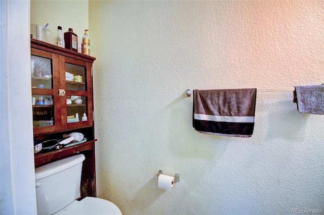 bathroom with toilet and a textured wall