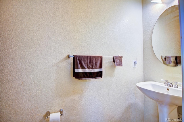 bathroom featuring a sink and a textured wall