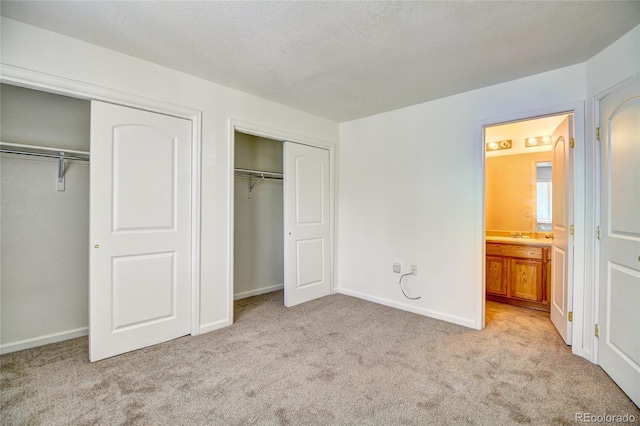 unfurnished bedroom featuring light colored carpet, two closets, and baseboards