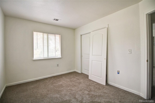 unfurnished bedroom featuring a closet, carpet flooring, baseboards, and visible vents