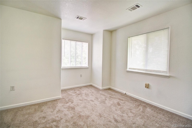 spare room featuring visible vents, a textured ceiling, baseboards, and carpet floors