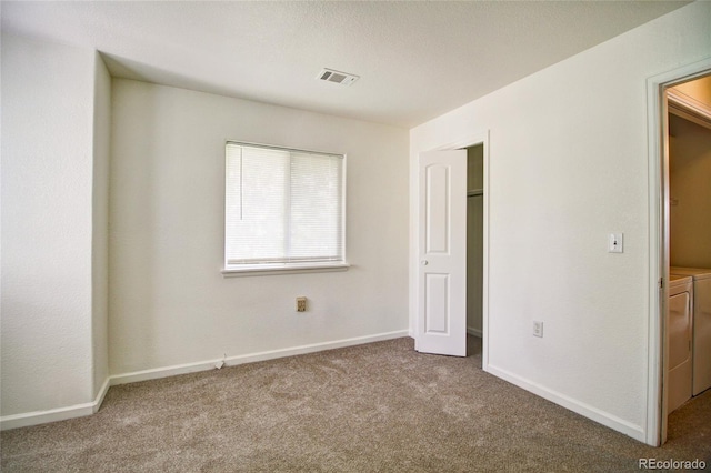 unfurnished bedroom featuring carpet floors, baseboards, visible vents, and separate washer and dryer