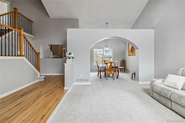 12551 W 84th Cir, Arvada, CO 80005 - living room featuring a high ceiling, visible vents, arched walkways, baseboards, and a chandelier