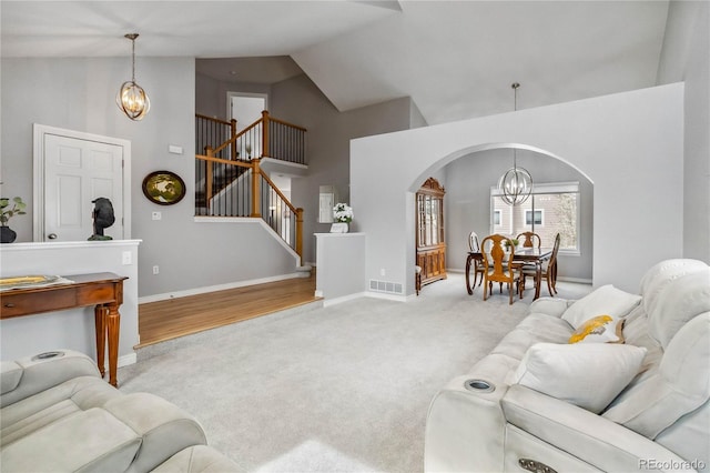 12551 W 84th Cir, Arvada, CO 80005 - living area featuring high vaulted ceiling, stairway, arched walkways, an inviting chandelier, and carpet