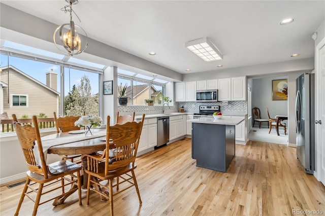 12551 W 84th Cir, Arvada, CO 80005 - kitchen with white cabinets, stainless steel appliances, backsplash, light countertops, and a kitchen island