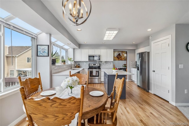 12551 W 84th Cir, Arvada, CO 80005 - dining space with light wood finished floors, baseboards, recessed lighting, and a notable chandelier