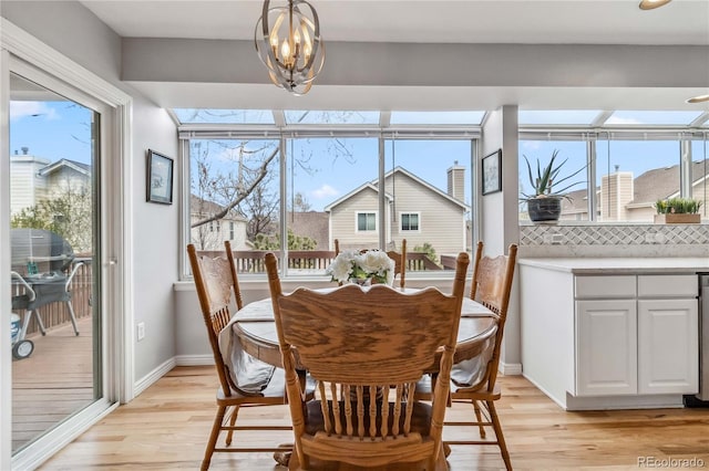 12551 W 84th Cir, Arvada, CO 80005 - dining area with light wood-style flooring, a notable chandelier, and plenty of natural light