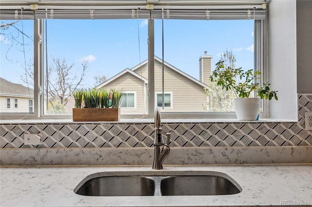 12551 W 84th Cir, Arvada, CO 80005 - details featuring light stone counters, decorative backsplash, and a sink