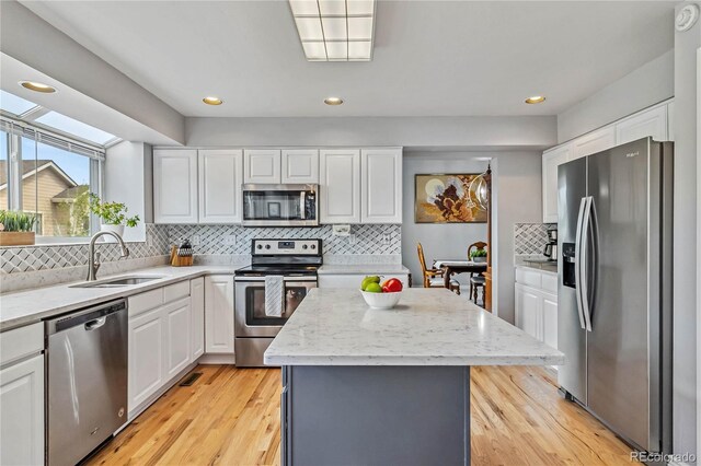 12551 W 84th Cir, Arvada, CO 80005 - kitchen featuring appliances with stainless steel finishes, white cabinets, backsplash, a center island, and recessed lighting