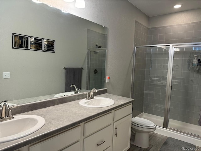 bathroom featuring wood-type flooring, vanity, toilet, and an enclosed shower