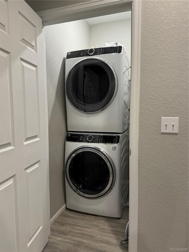 clothes washing area featuring light hardwood / wood-style floors and stacked washer / drying machine