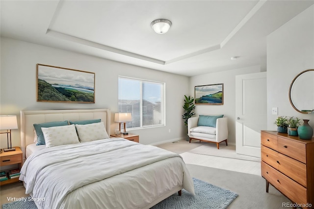 carpeted bedroom with baseboards and a tray ceiling