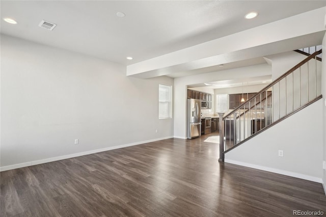 unfurnished living room featuring baseboards, visible vents, dark wood-style floors, stairs, and recessed lighting