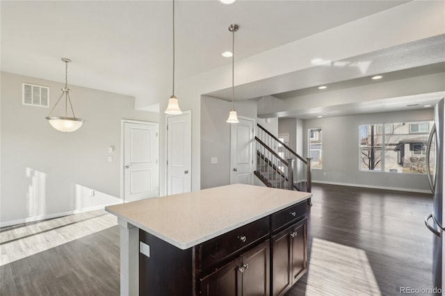 kitchen featuring dark brown cabinetry, dark wood-type flooring, visible vents, baseboards, and open floor plan