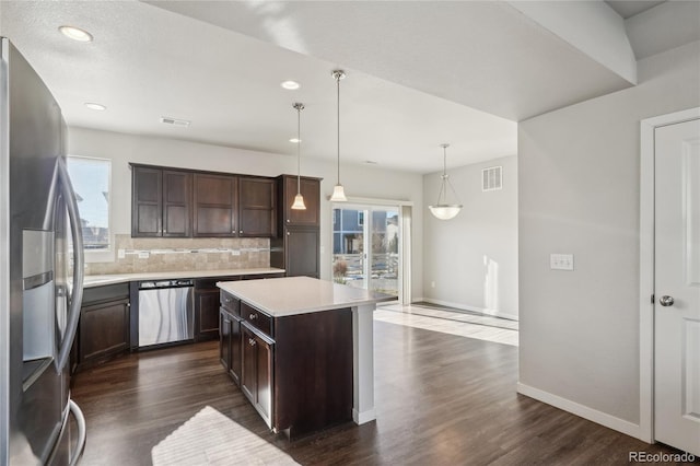 kitchen featuring stainless steel appliances, visible vents, dark brown cabinets, light countertops, and decorative backsplash