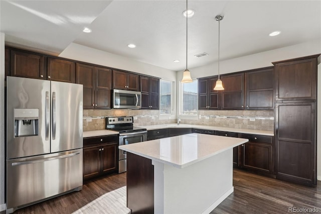 kitchen with dark brown cabinetry, visible vents, dark wood-style flooring, hanging light fixtures, and stainless steel appliances