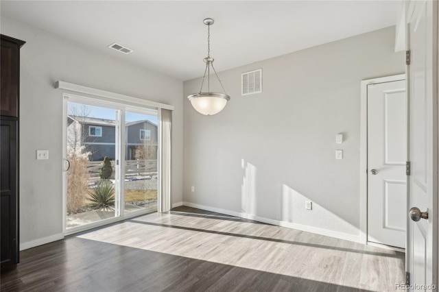 unfurnished dining area featuring wood finished floors, visible vents, and baseboards