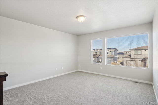 unfurnished room featuring baseboards, a textured ceiling, visible vents, and carpet flooring