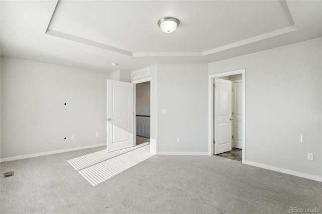 unfurnished bedroom with carpet, visible vents, baseboards, and a raised ceiling