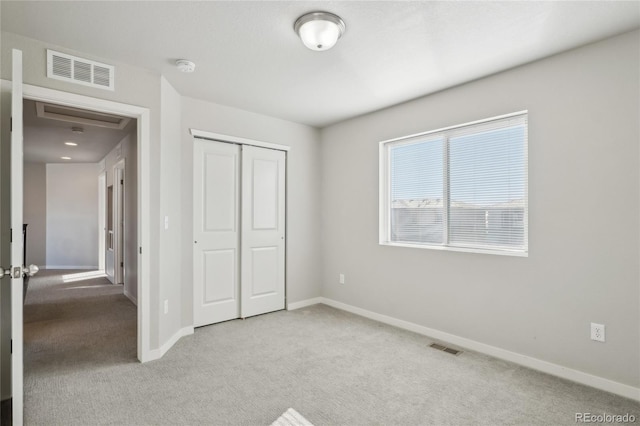 unfurnished bedroom featuring light colored carpet, a closet, visible vents, and baseboards