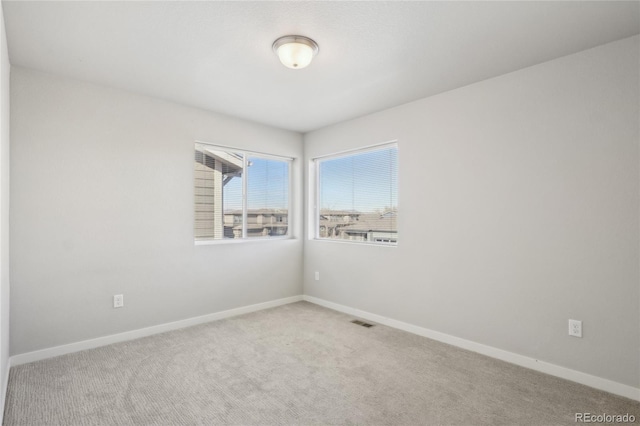 spare room featuring carpet floors, visible vents, and baseboards