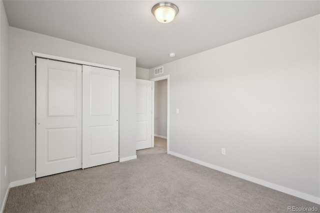 unfurnished bedroom with a closet, carpet flooring, visible vents, and baseboards