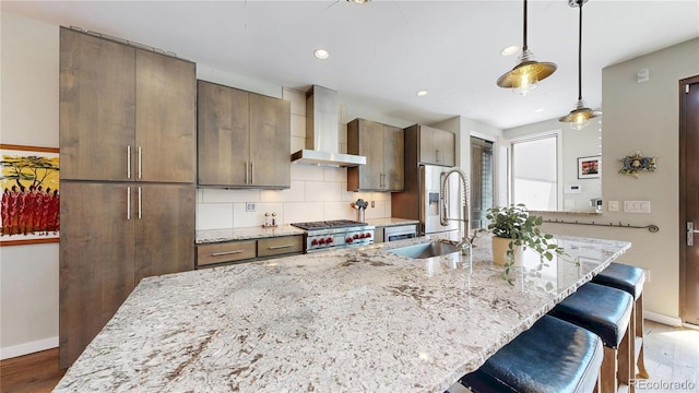1426 S Pearl St, Denver, CO 80210 - kitchen with wall chimney range hood, a breakfast bar area, a large island with sink, wood finished floors, and recessed lighting